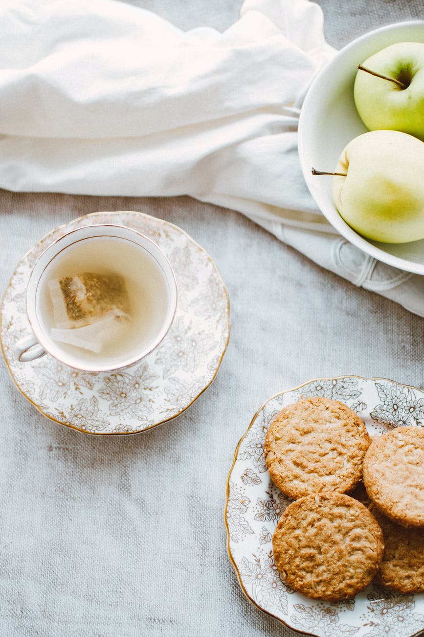 bowl of apples plate of biscuits and teacup